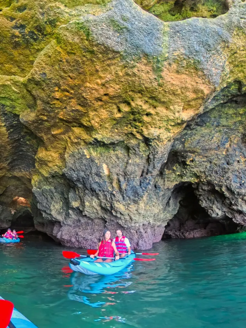 Couple in a kayak at the entrance of the Pirate Cave, Algarve – dark cave interior contrasts with bright turquoise sea outside