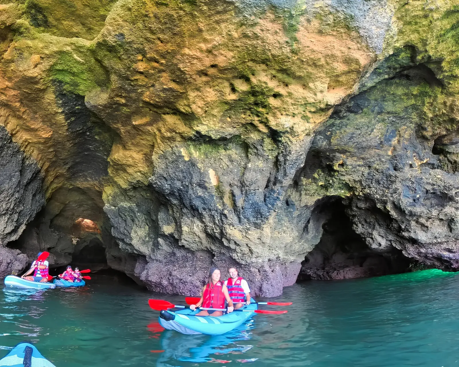 Kayakers exploring the interior of the Pirate Cave along the Algarve coast – dramatic rock formations and calm dark water inside