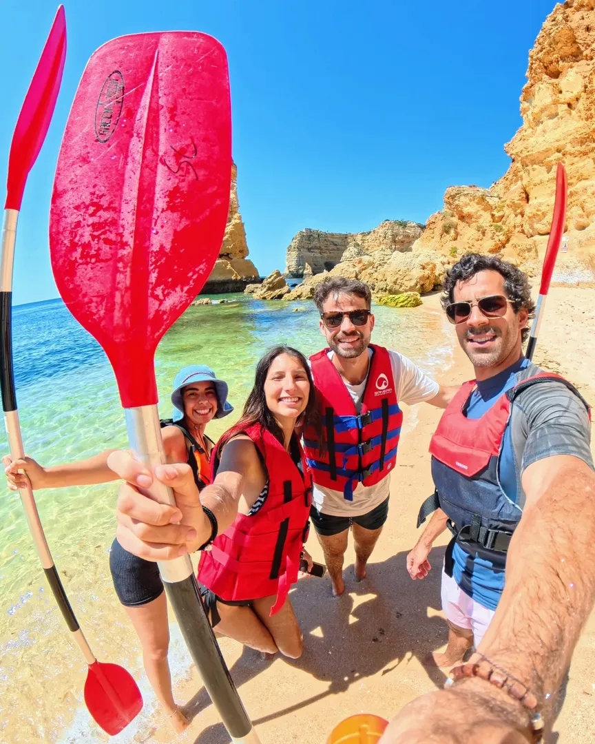 Group selfie of kayak tour guests at Praia da Marinha wearing life vests – one of the stops on the Salty Cliffs Benagil tour