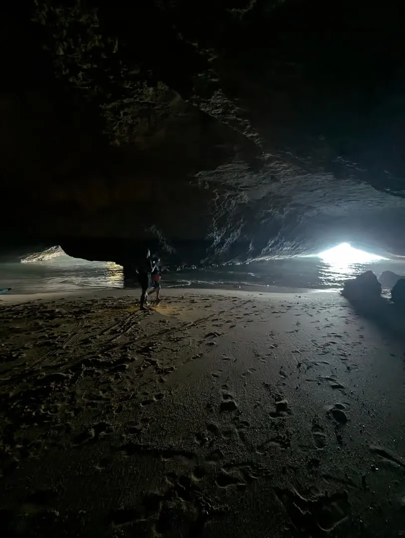 A hidden sandy beach inside a dark sea cave along the Algarve coast – accessible only by kayak or swimming through the cave entrance