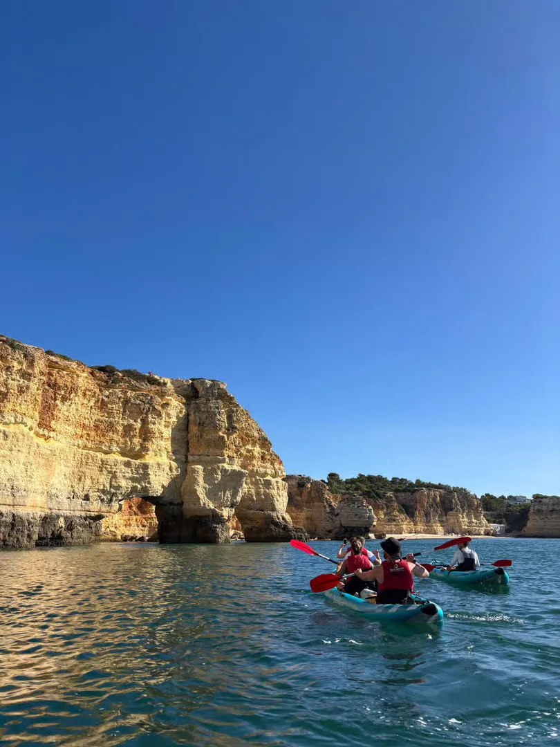 Couple posing in their kayak with towering Benagil limestone cliffs rising behind them – Algarve kayak tour