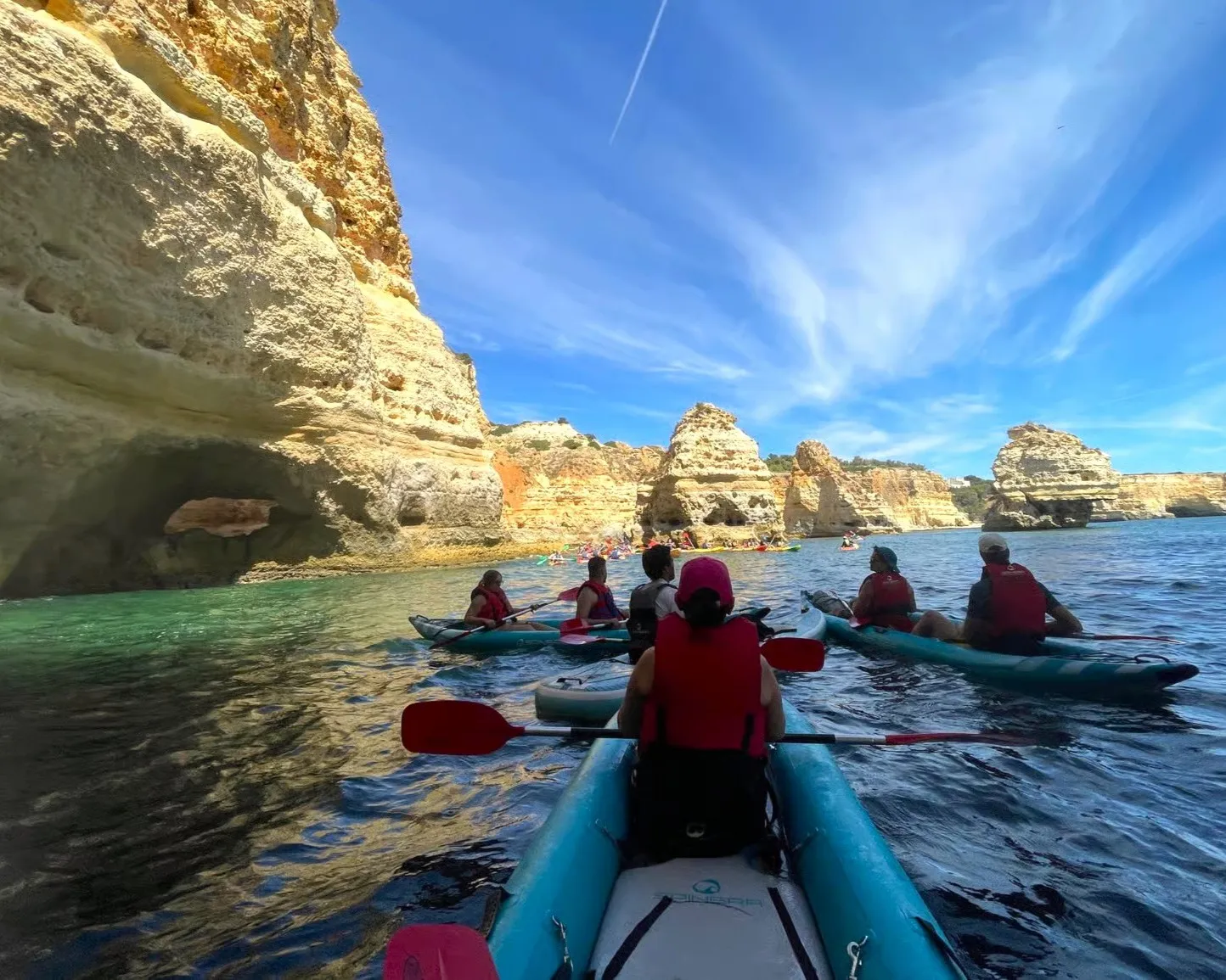 Group of kayakers paddling near the distinctive rock formations at Praia da Marinha, one of Europe's most beautiful beaches